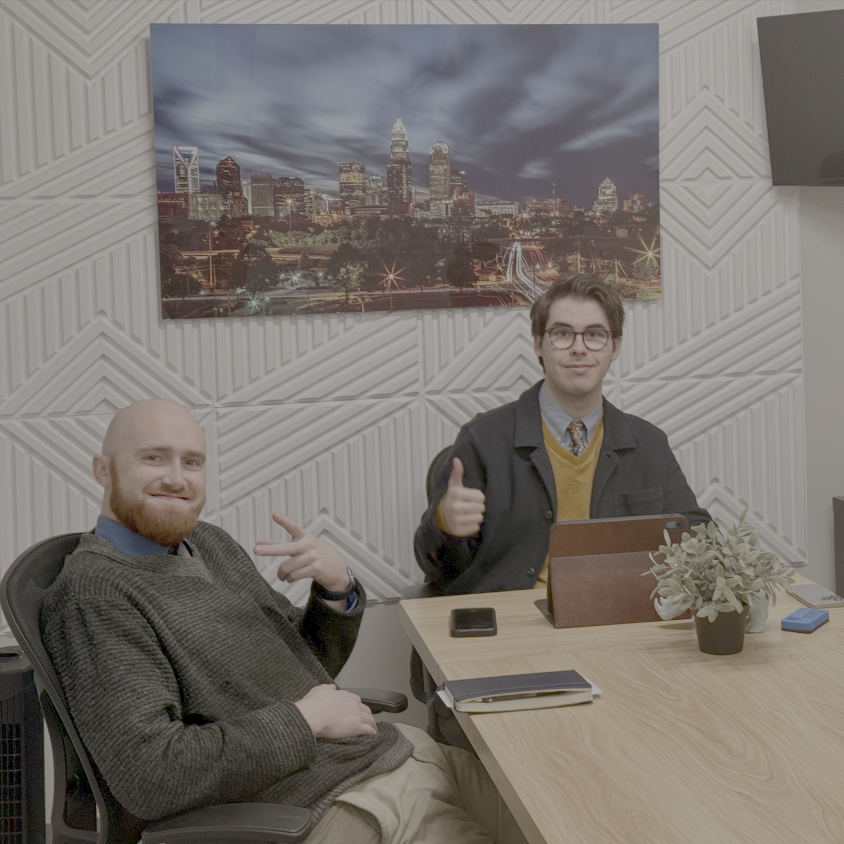 KULO Management team members collaborating in Charlotte office with city skyline